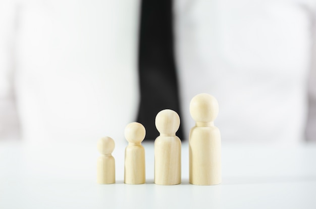 Four wooden figures placed in a row increasing in size in front of a businessman in conceptual image for personal development or becoming a leader