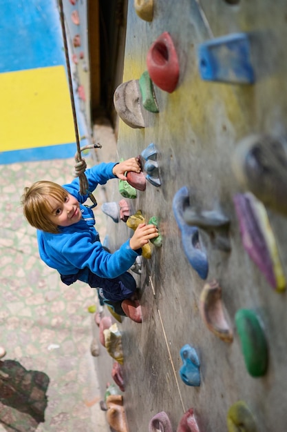 Four year old boy climbs the climbing wall in the hall