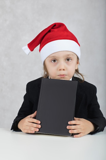 of four years in Santa's hat and black book sits at the table. Closeup
