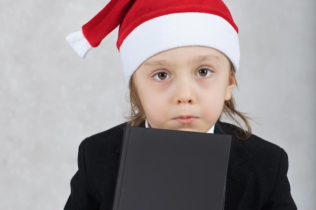 of four years in Santa's hat and black book sits at the table. Closeup