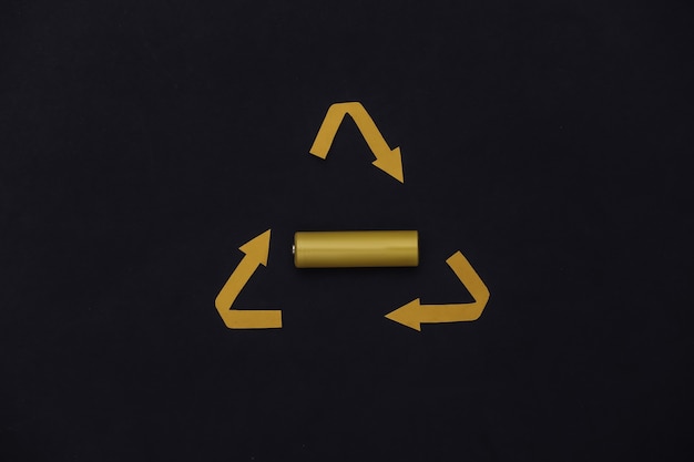 Four yellow aa battery with recycled arrows sign on black\
background. top view