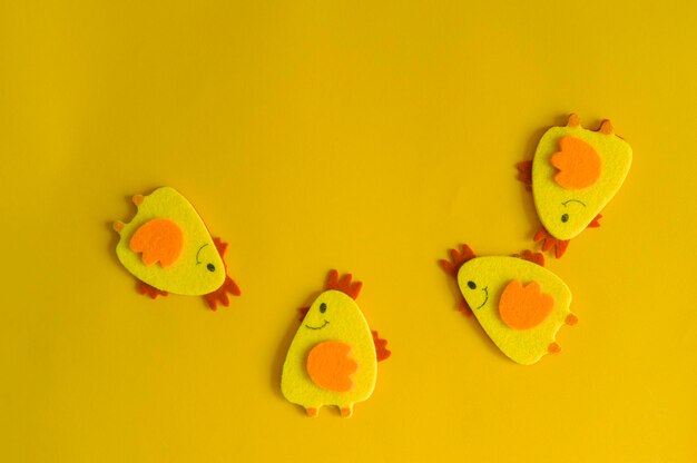 Four yellow felt decorative chickens arranged in a semicircle on a yellow background minimal concept cute easter card with a copy of the place for the text
