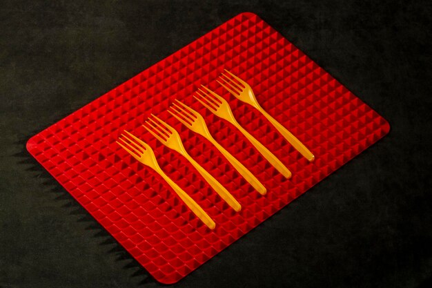 Four yellow forks on a red rug