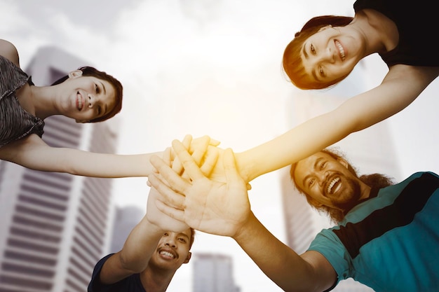 Four young people joining their hands in city