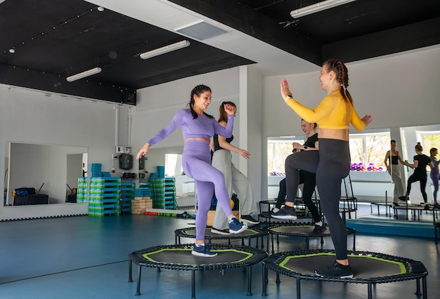 Four young women on trampoline young fitness girls trains on fitness studio