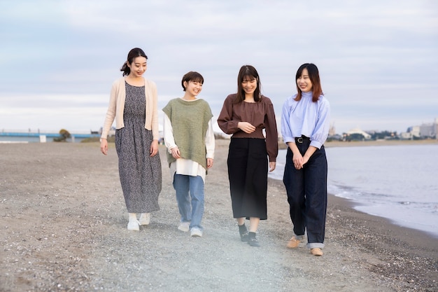 夕暮れの海を歩く4人の若い女性