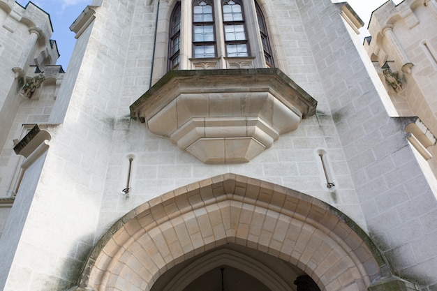 Fragment of ancient castle with arched entrance and tall windows