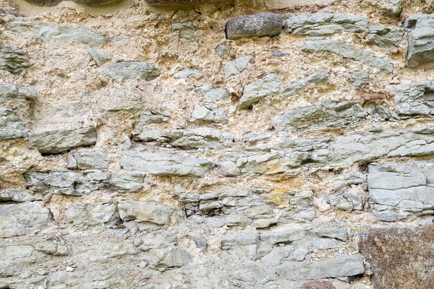 石灰岩で作られた古代中世の要塞の壁の断片。ヴィンテージの背景。天然の古い石。中世風のパターン。中世の建築の要素。セレクティブフォーカス。