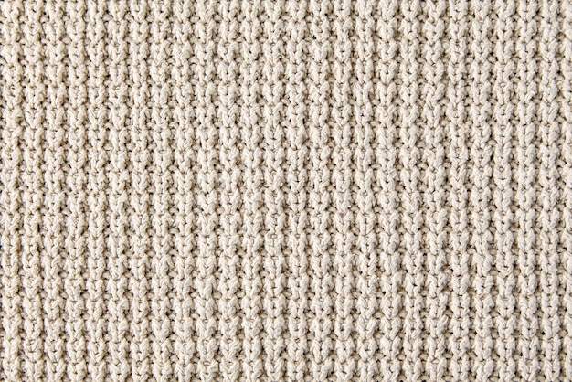 Fragment of beige knitted clothes of rough knitting