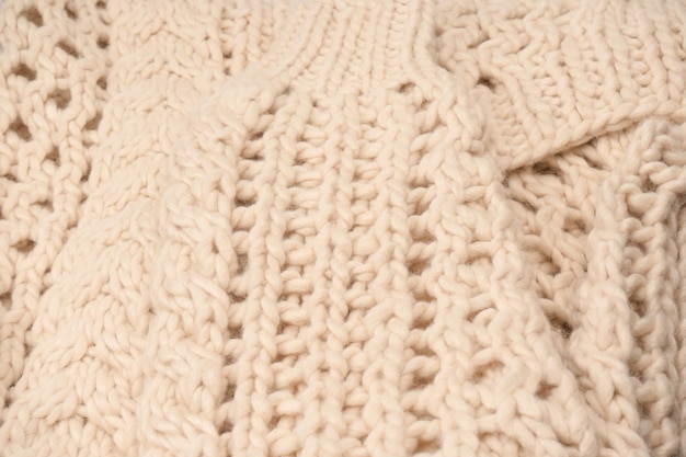A fragment of beige knitted fabric knitted from white sheep wool