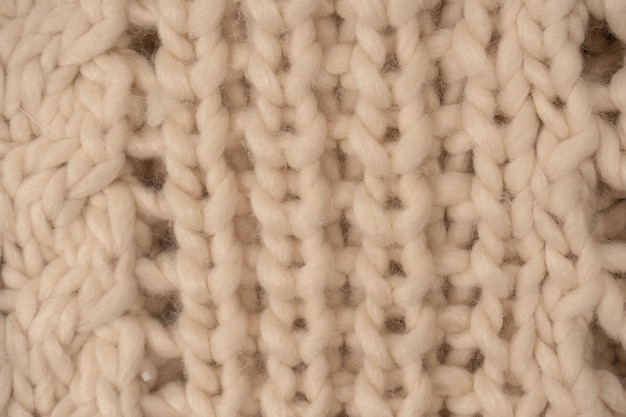 A fragment of beige knitted fabric knitted from white sheep wool