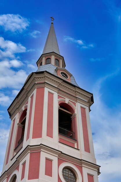 Fragment of the bell tower of a pink Christian church. Church bell tower against the sky