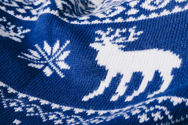 Fragment of a blue knitted sweater with a white deer pattern