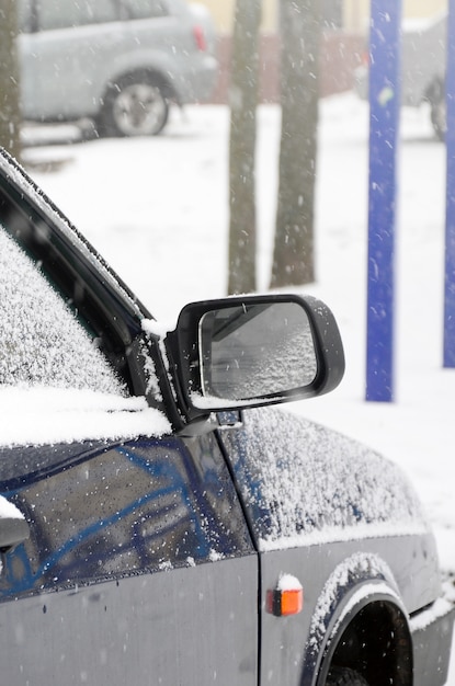 Fragment of the car under a layer of snow after a heavy snowfall. The body of the car is covered with white snow