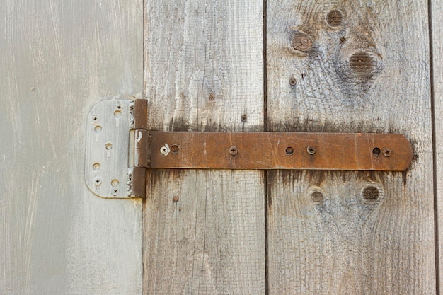 Fragment of a closed old wooden gate with old rusty hinges.