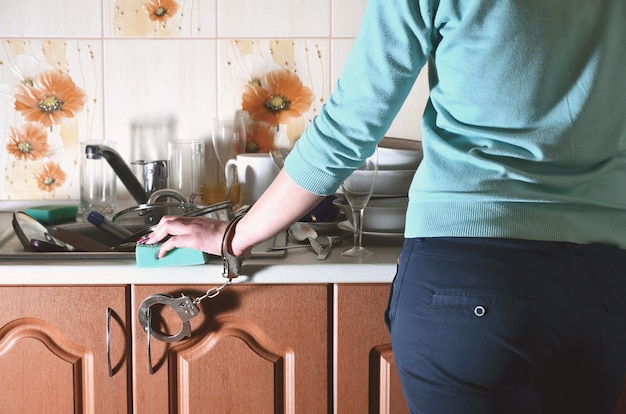 Foto frammento del corpo femminile, ammanettato al bancone della cucina