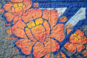 Photo fragment of graffiti drawings the old wall decorated with paint stains in the style of street art culture orange flower
