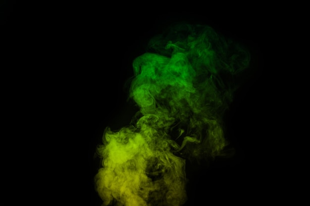 Fragment of green yellow curly steam smoke isolated on a black background, close-up. Create mystical Halloween photos. Abstract background, design element