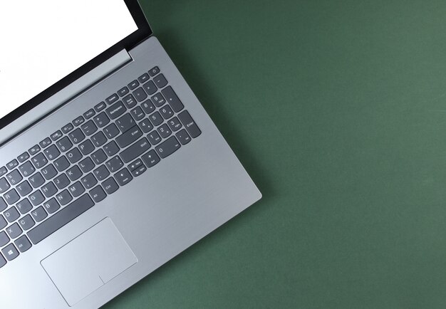 Fragment of laptop with a white screen on a green table. 