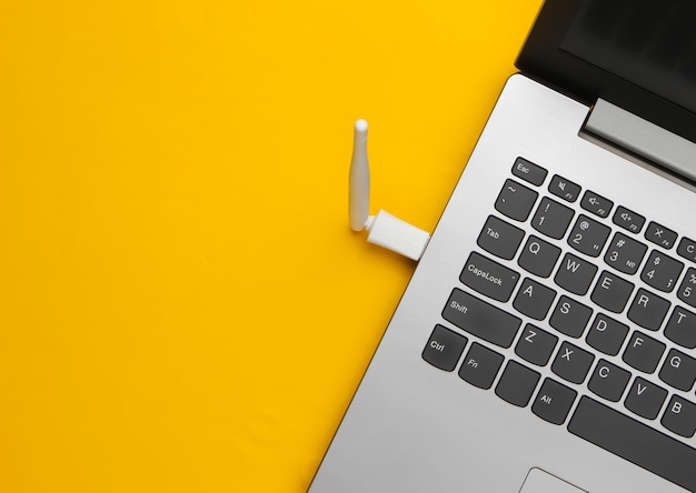 Fragment of a laptop with a wifi antenna on a yellow.