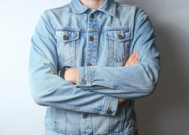 Fragment of a man dressed in a denim jacket and beige trousers.
