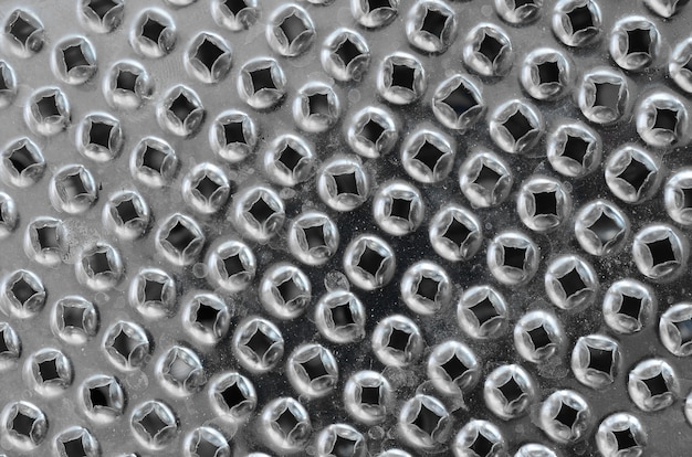 A fragment of a metal chrome grater close-up. Texture of blades for grinding food