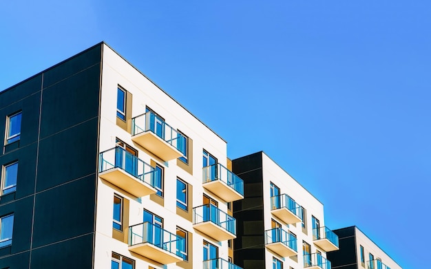 Fragment of Modern residential apartment with flat buildings exterior. Detail of New luxury house and home complex. Part of City Real estate property and condo architecture. Copy space. Blue sky