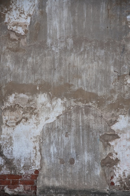 fragment of an old brick wall with concrete plaster and remnants of multicolored paint