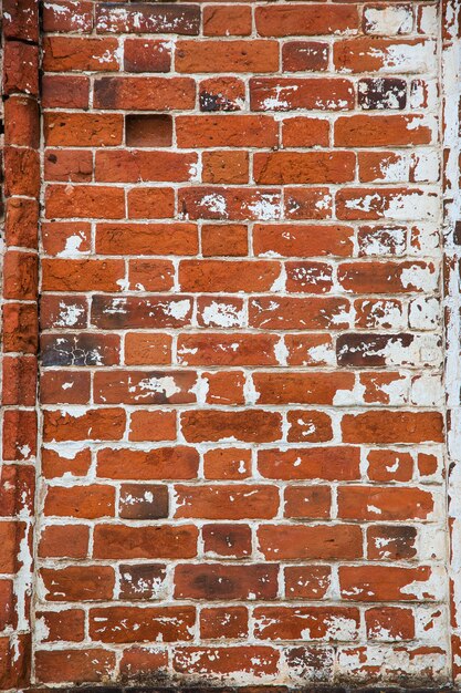 fragment of an old brick wall with concrete plaster and remnants of multicolored paint