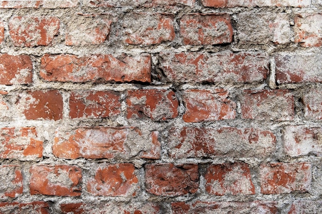 Fragment of an old red brick wall with traces of plaster