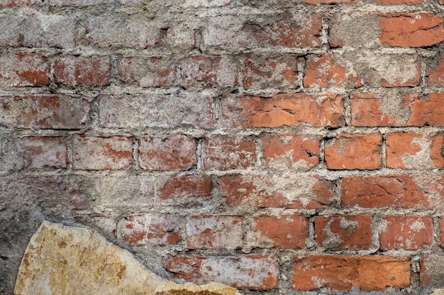 Fragment of an old red brick wall with traces of plaster