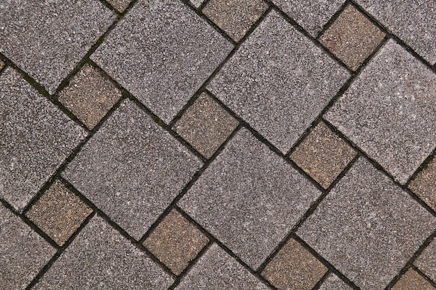 Fragment of sidewalk made of square concrete tiles of different sizes