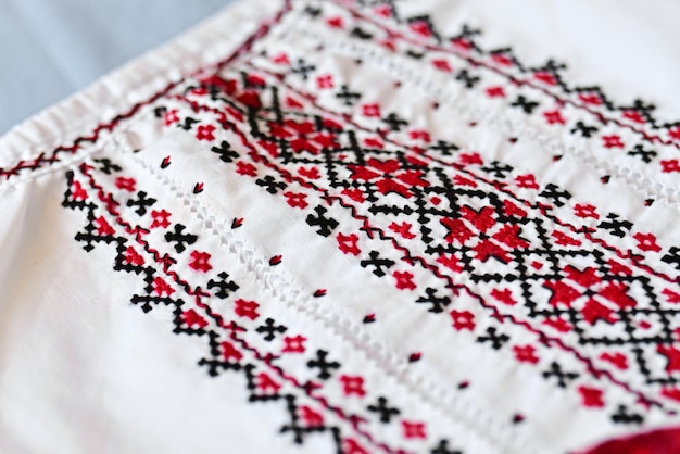 Fragment of Ukrainian national dress Vyshyvanka ethnic clothing with embroidery patterns red and black threads Closeup shot copy space