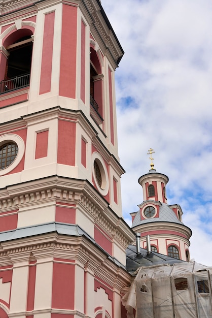 Fragment van de klokkentoren van een roze christelijke kerk. Kerkklokkentoren tegen de hemel