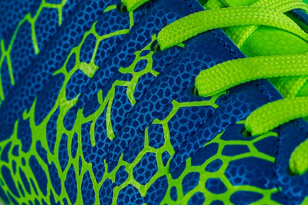 Fragment van een blauwe sneaker met groene veters close-up Sneakertextuur