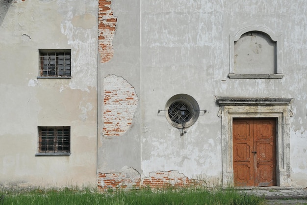 Fragment of the wall of the old monastery with vintage door and windows Ancient vintage background