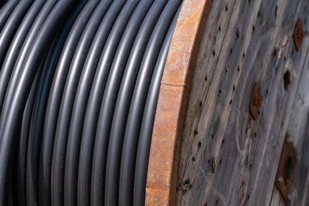 Фрагмент деревянной катушки с черным электрическим кабелемx9