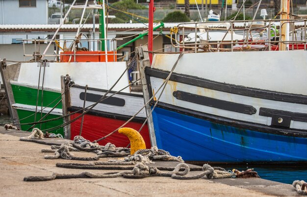 Фрагменты носовой части рыбацких лодок, привязанные веревками к причалу.