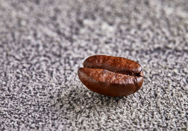 Chicco di caffè profumato con ombra su uno spazio concreto.