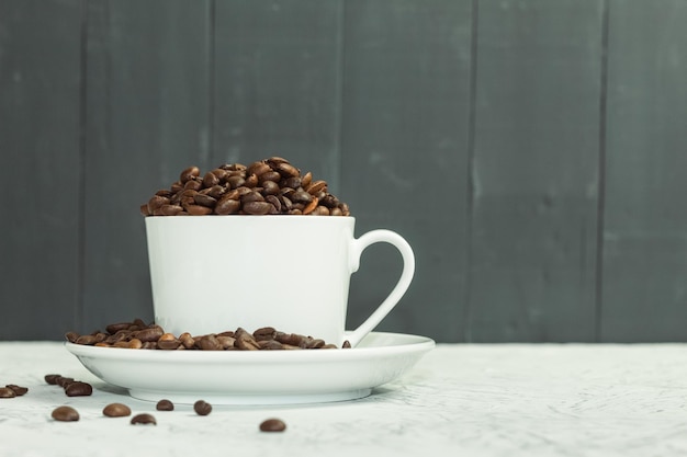 나무 배경에 있는 흰색 컵에 있는 향기로운 커피 곡물
