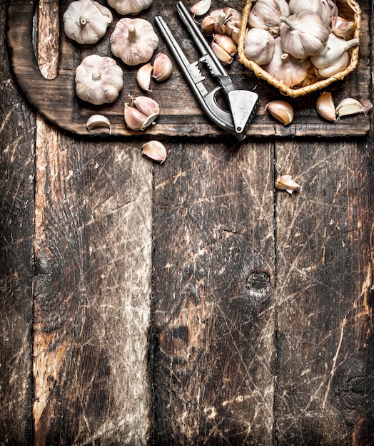 Photo fragrant garlic with a press tool on a wooden board. on rustic table.