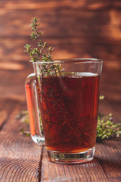 Ароматный травяной чай с пучками тимьяна в стеклянной кружке