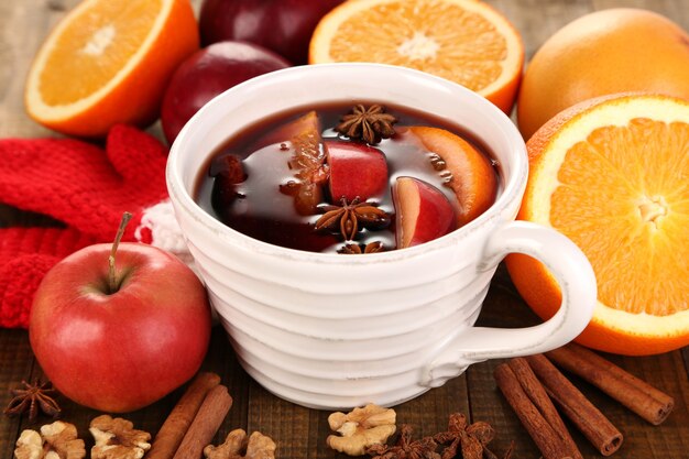 Fragrant mulled wine in bowl on wooden table close-up