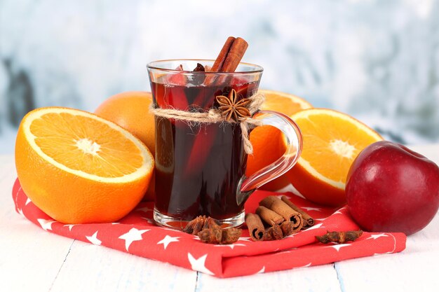 Fragrant mulled wine in glass on napkin on winter background