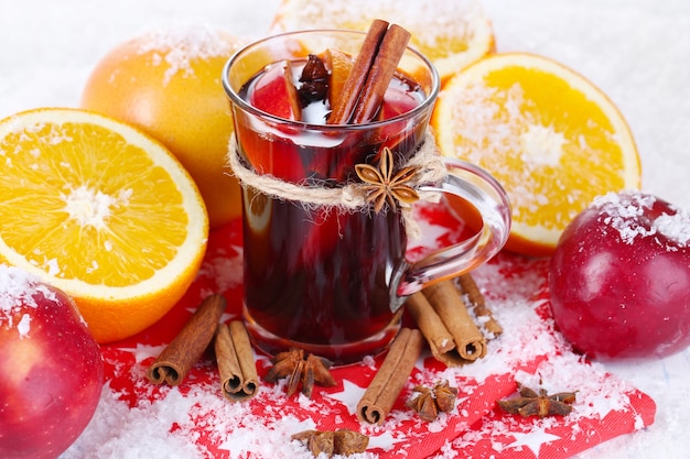 Fragrant mulled wine in glass on snow close-up