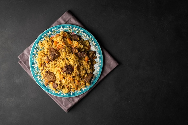 Foto pilaf fragrante con carne e verdure vista dall'alto su un piatto su sfondo nero con spazio copia