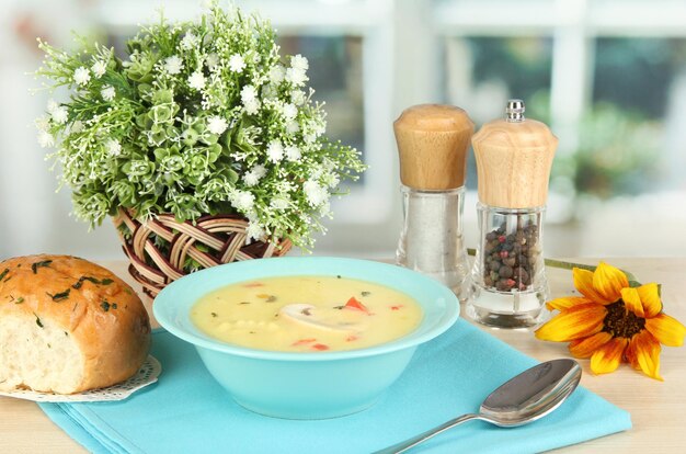 Fragrant soup in blue plate on table on window background closeup