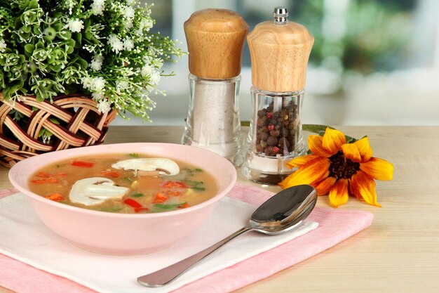 Fragrant soup in pink plate on table on window background closeup