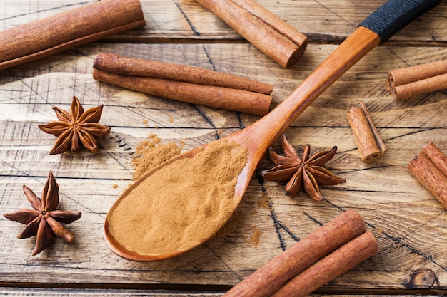 Fragrant spices cinnamon sticks and ground, star anise on wooden background.