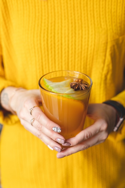 Fragrant tea close-up in the hands of a girl in a yellow sweater